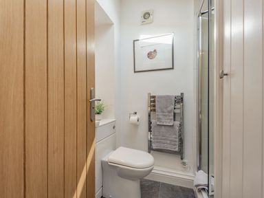 A bathroom with a toilet a towel rail with towels a shower and a wooden door at 2 Bryn Tirion in Llan Ffestiniog