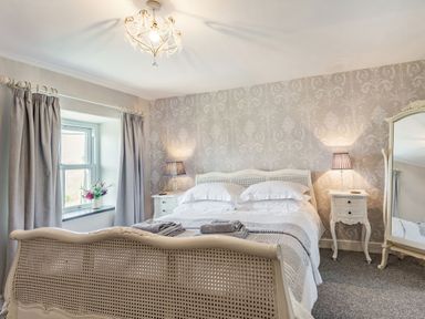 A bedroom with a bed framed by nightstands with lamps and a mirror at 2 Bryn Tirion in Llan Ffestiniog