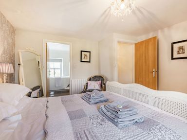 A bedroom with a bed covered in folded towels a mirror lamp an armchair and an open door leading to a bathroom at 2 Bryn Tirion in Llan Ffestiniog
