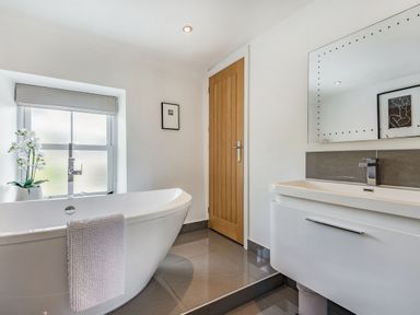 A bathroom with a freestanding bathtub and a sink under a mirror at 2 Bryn Tirion in Llan Ffestiniog