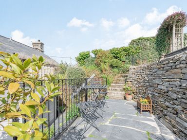 An outdoor patio area with metal table and chairs stone wall stairs and plants at 2 Bryn Tirion in Llan Ffestiniog
