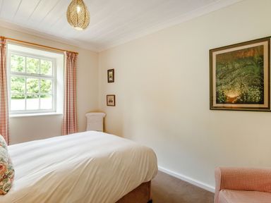 A bedroom with a bed beside a window and framed pictures on the walls at Reiver's Rest in Hesleyside near Bellingham