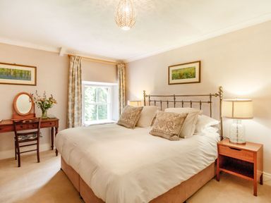 A bedroom with a double bed bedside tables a desk with a chair and window at Reiver's Rest in Hesleyside near Bellingham