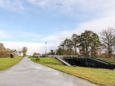 A gravel pathway with grassy banks leading to canal locks and a building in the distance at Glen Dessary Corpach near Fort William