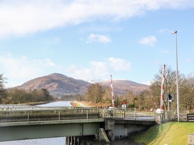 A bridge over a canal with mountains and trees in the background at Glen Dessary in Corpach near Fort William