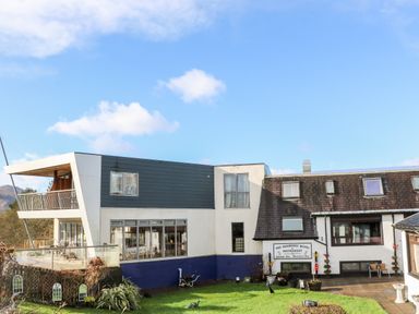 Exterior view of The Moorings Hotel and Restaurant with lawn and patio area at Glen Dessary in Corpach near Fort William