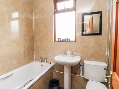 A bathroom with a bathtub a pedestal sink and a toilet with a window and a mirror at Glen Dessary in Corpach near Fort William