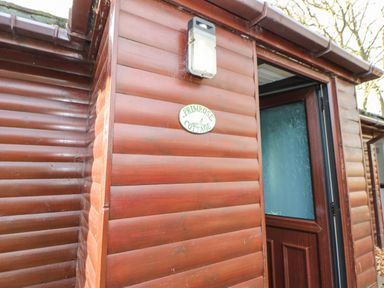 A wooden exterior wall with an outdoor light and a sign that reads primrose cottage at Primrose Lodge in Saltburn-by-the-Sea