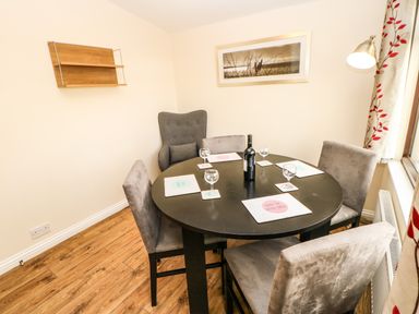 A dining room with a round black table and five grey chairs at Primrose Lodge in Saltburn-by-the-Sea