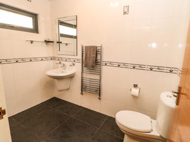 A bathroom with a toilet sink mirror towel rack and tiled walls at Primrose Lodge in Saltburn-by-the-Sea