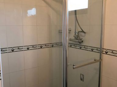 A shower enclosure with tiled walls and a glass door at Primrose Lodge in Saltburn-by-the-Sea
