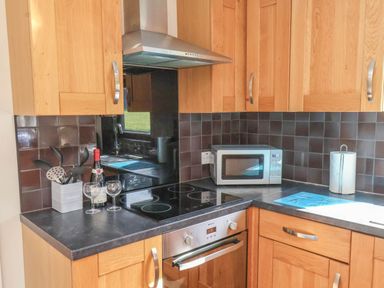 A kitchen with cabinets, a microwave, and wine glasses at Primrose Lodge in Saltburn-by-the-Sea
