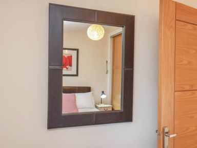 A mirror reflecting a bed and lamp at Primrose Lodge in Saltburn-by-the-Sea