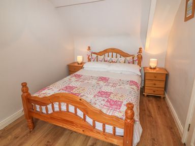A bedroom with a wooden bed and two wooden bedside tables with lamps at Nanas House in Allihies County Cork