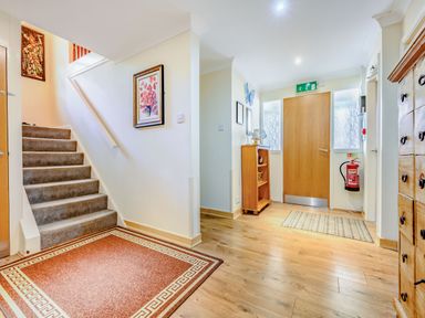 An entrance area with wooden floor a staircase a wooden door a fire extinguisher and wooden furniture at Eden House in Bardsea