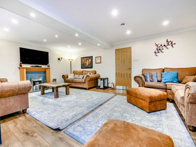 A living room with brown sofas a wooden coffee table and a wall mounted tv at Eden House in Bardsea
