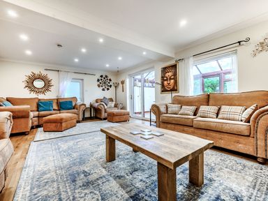 A living room with brown sofas wooden coffee table rugs and wall decorations at Eden House in Bardsea