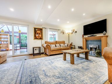 A living room with brown sofas wooden coffee table and wall-mounted TV at Eden House in Bardsea