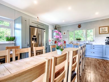A kitchen with wooden dining table and chairs blue cabinets and stainless steel refrigerator at Eden House in Bardsea