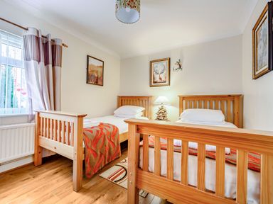 A bedroom with two single wooden beds with orange patterned blankets and a lamp on a bedside table at Eden House Bardsea