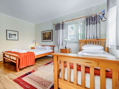 A bedroom with two single beds wooden furniture a rug and framed pictures on walls at Eden House Bardsea