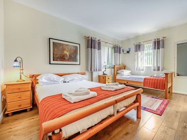 A bedroom with a double bed and a single bed with wooden frames and bedside tables at Eden House in Bardsea