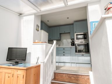 A small kitchen with blue cabinets and appliances at Lyndhurst Cottage in Beadnell