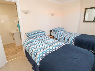A bedroom with two single beds a nightstand and a mirror at Lyndhurst Cottage in Beadnell