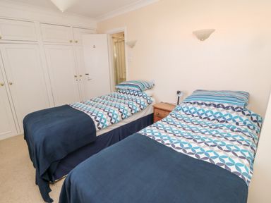 A bedroom with two single beds side by side with patterned bedding and a wooden nightstand between them at Lyndhurst Cottage in Beadnell