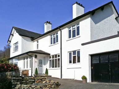 A white two-story house with black garage doors and stone wall at Llechwedd in Dolgellau
