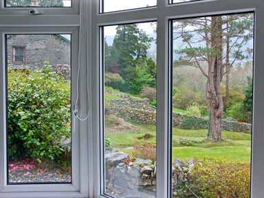 A landscape view with trees shrubs stone walls and a building seen through three window panes at Llechwedd in Dolgellau