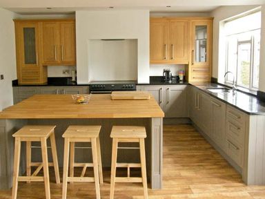 A kitchen with wooden stools at a wooden island and cabinets at Llechwedd in Dolgellau