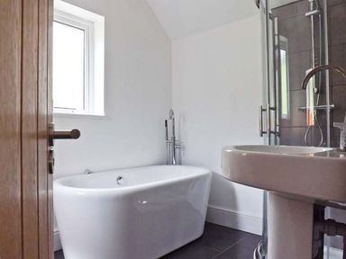 A bathroom with a freestanding bathtub a sink and a glass shower enclosure at Llechwedd in Dolgellau
