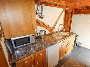 A kitchen counter with a microwave kettle sink dishwasher and utensils at The Shippon in Llechwedd The Conwy Valley
