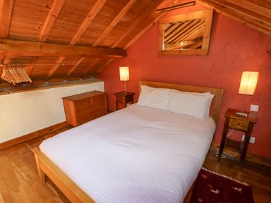 A bedroom with a wooden bed white bedding two bedside tables with lamps a chest of drawers and wooden ceiling at The Shippon in Llechwedd The Conwy Valley