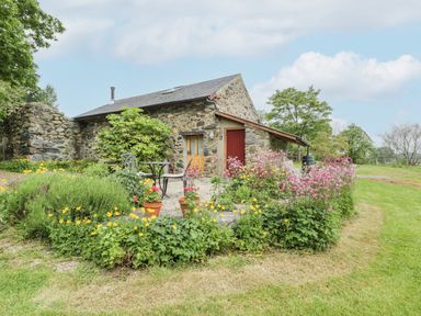 A stone cottage with a small garden and outdoor seating area at The Shippon in Llechwedd The Conwy Valley