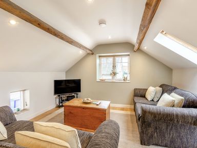 A living room with sofas a wooden coffee table and a television at Upstairs Downstairs Cottage in Snainton near Scarborough