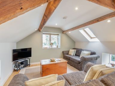 A living room with sofas a wooden coffee table a television and exposed wooden beams at Upstairs Downstairs Cottage in Snainton near Scarborough
