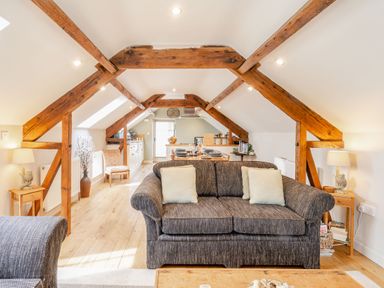 A living room and dining area with wooden beams and sofas at Upstairs Downstairs Cottage in Snainton near Scarborough
