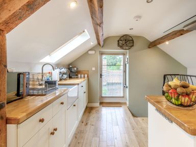 A kitchen with wooden countertops a sink a microwave coffee machine and a fruit basket at Upstairs Downstairs Cottage in Snainton near Scarborough