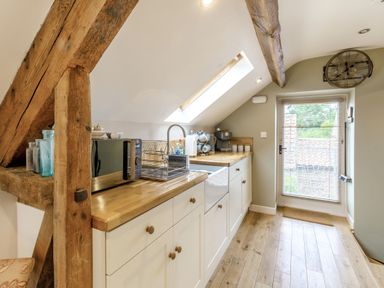 A kitchen with wooden countertops a microwave a coffee machine and wooden beams at Upstairs Downstairs Cottage in Snainton near Scarborough