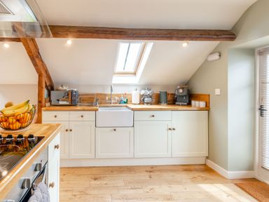 A kitchen with wooden countertops a sink a coffee machine and a fruit bowl at Upstairs Downstairs Cottage in Snainton near Scarborough