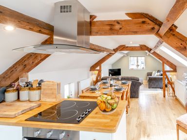 An open kitchen and living area with wooden beams and dining table at Upstairs Downstairs Cottage in Snainton near Scarborough