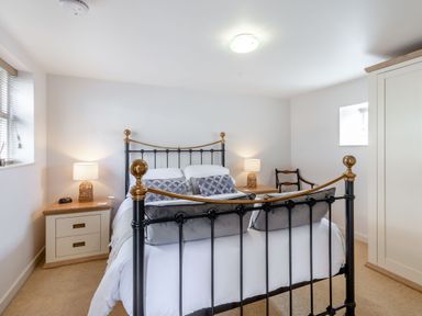 A bedroom with a black and gold metal bed frame two bedside tables with lamps a wooden chair and a cream wardrobe at Upstairs Downstairs Cottage in Snainton near Scarborough