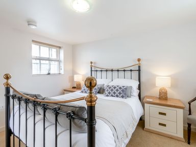 A bedroom with a metal bed frame a window and two bedside tables with lamps at Upstairs Downstairs Cottage in Snainton near Scarborough
