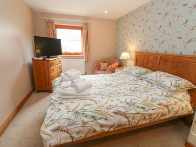 A bedroom with a bed and television at Cooper Cottage in Potto near Stokesley