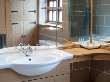 A bathroom sink with a chrome faucet and wooden countertop with mirrors at Yew Tree Cottage in Little Malvern near Malvern