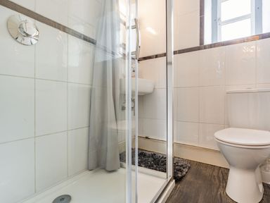 A bathroom with a shower, toilet, sink, and a window at Hillside Cottage in Peasedown St John near Bath