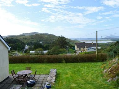 A garden with a patio table and chairs overlooking hills and a distant body of water at The Bay in Caherdaniel County Kerry