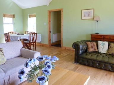 A living room with two sofas a table with blue flowers and a dining table with chairs at The Bay in Caherdaniel County Kerry